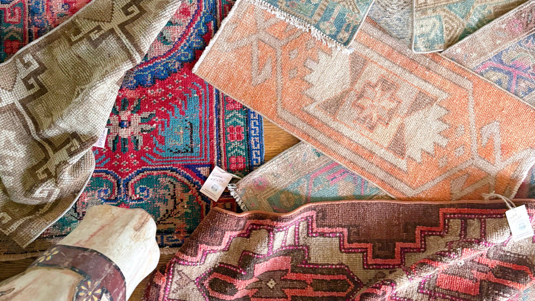 Collection of various patterned rugs on a wooden floor.